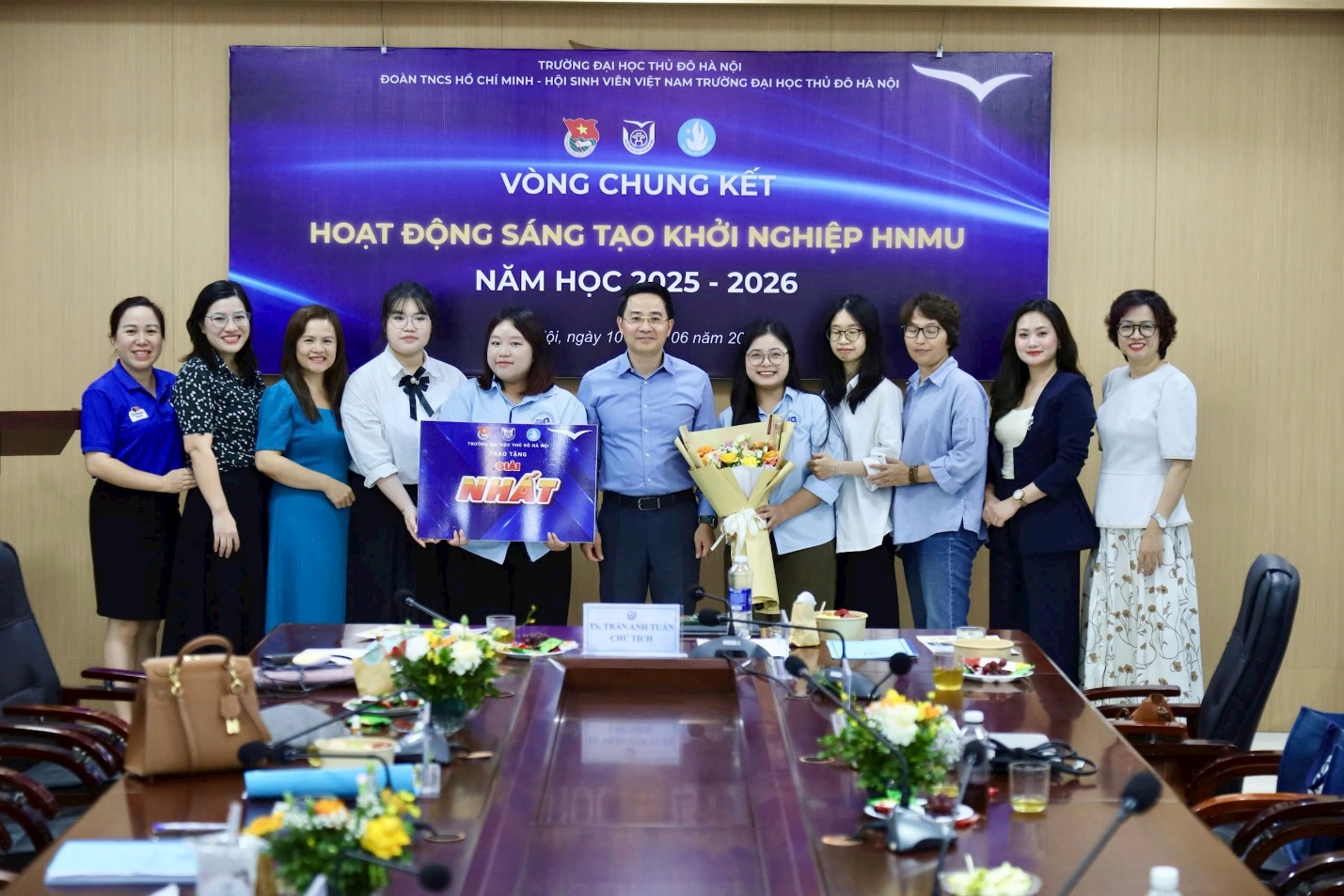 A group of people standing in front of a banner
Description automatically generated